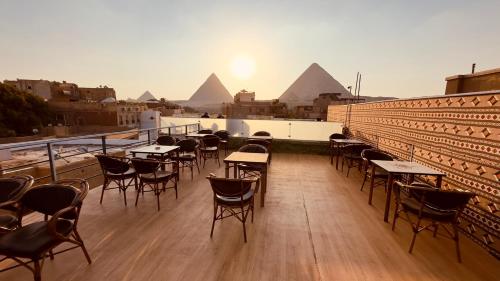 a deck with tables and chairs on a building with pyramids at Locanda pyramids view in Cairo