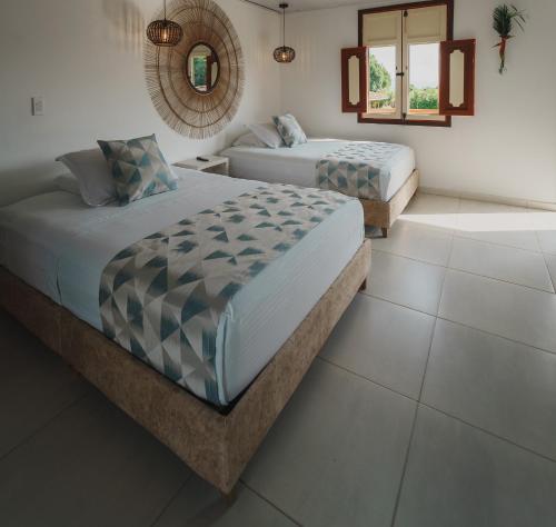 a bedroom with two beds and a mirror on the wall at Hotel Terra Tacuara in Armenia