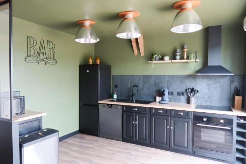 une cuisine avec un réfrigérateur noir et quelques lumières dans l'établissement Grange La Rouge - gîte Corrèze, à Ayen