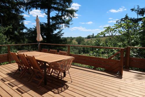 une terrasse en bois avec une table, des chaises et un parasol dans l'établissement Grange La Rouge - gîte Corrèze, à Ayen