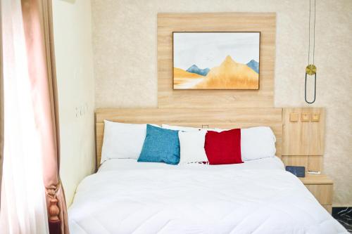 a bedroom with a white bed with colorful pillows at Cozy Cove Residence in Kadobunkuro
