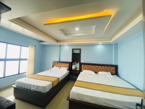 two beds in a room with blue walls at Hill inn homestay in Sukhia Pokhari