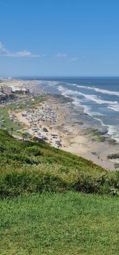 a beach with a crowd of people and the ocean at Hotel Ficare Torres in Torres