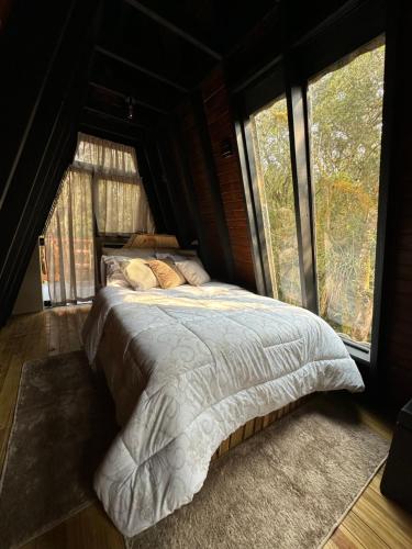 a bedroom with a bed in a room with windows at Chalé Refúgio da Mata in São José dos Pinhais