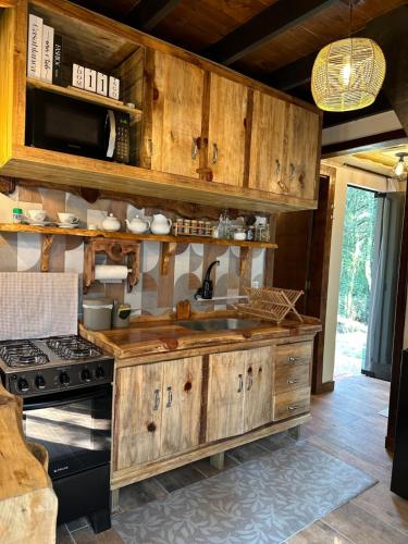 a kitchen with a sink and a stove at Chalé Refúgio da Mata in São José dos Pinhais