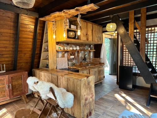 a kitchen with wooden cabinets and chairs in a room at Chalé Refúgio da Mata in São José dos Pinhais