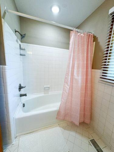 a bathroom with a bath tub with a pink shower curtain at Sumner Ave in Gallatin