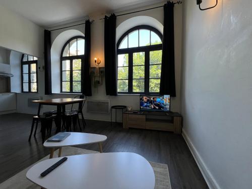 - un salon avec deux tables et deux fenêtres dans l'établissement Le Bourgeois Grand T2, à Carcassone