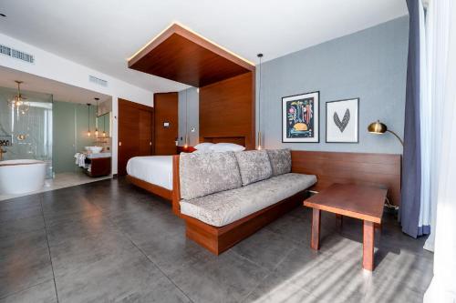 a bedroom with a bed and a couch and a table at MARQUEE Playa Hotel in Playa del Carmen
