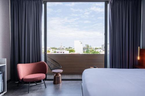 a hotel room with a bed and a chair and a window at MARQUEE Playa Hotel in Playa del Carmen