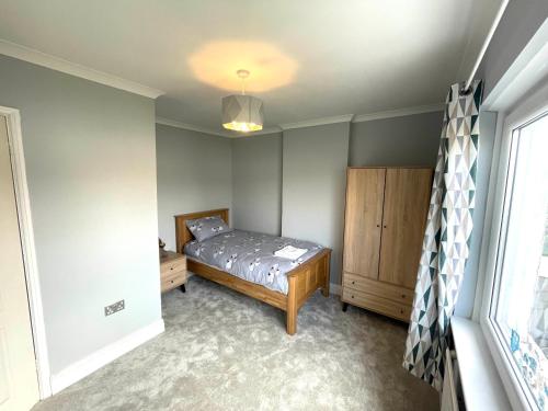 a bedroom with a bed and a dresser and a window at Cozy 3 Bedroom Home in Port Talbot