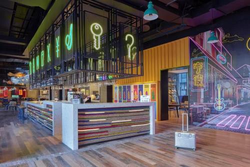 a restaurant with a counter with neon signs on the wall at Moxy Ningbo Old Bund in Ningbo