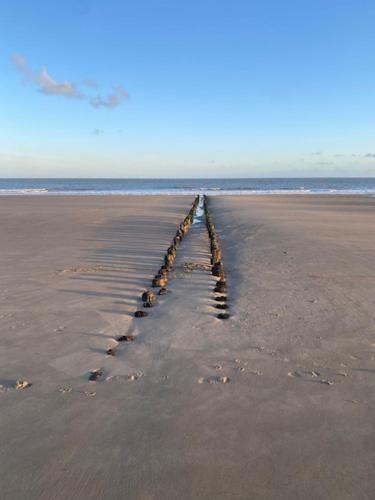 an empty beach with a pier in the sand at Hotel Villa Verdi in Knokke-Heist