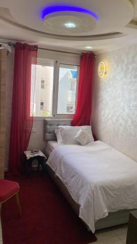 a bedroom with a white bed with red curtains at Le Familial in Riffiene