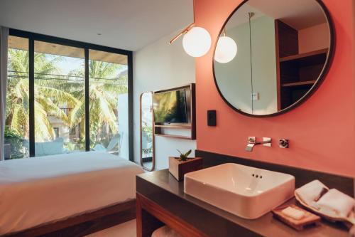 a bedroom with a bed and a sink and a mirror at CALIXTA Hotel in Playa del Carmen