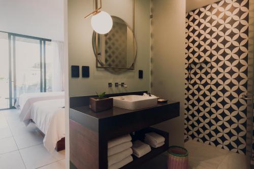 a bathroom with a sink and a bed and a mirror at CALIXTA Hotel in Playa del Carmen