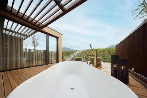 a room with a white table on a wooden deck at Hotel Seehof Nature Retreat in Naz-Sciaves