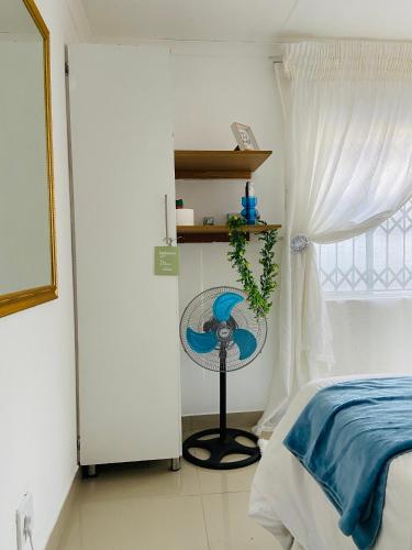 a bedroom with a bed and a fan next to a window at The Fern Corner Guest House 1 in Tzaneen