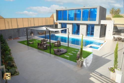 a villa with a swimming pool in front of a building at Harz chalet in Sowayma