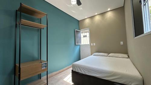 a bedroom with a bed and a blue wall at Suíte 01 • Praia das Pitangueiras in Guarujá