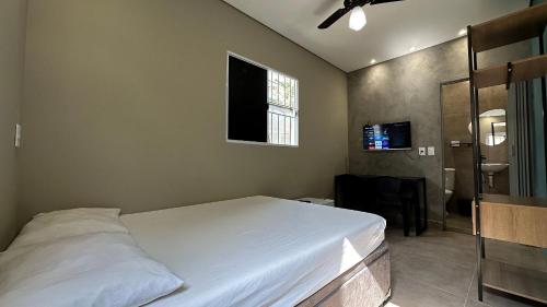 a bedroom with a bed and a flat screen tv at Suíte 01 • Praia das Pitangueiras in Guarujá