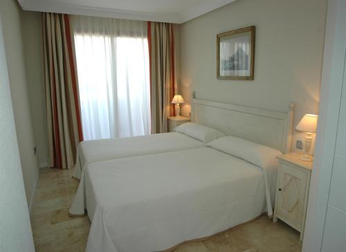 Un dormitorio blanco con dos camas y una ventana. en Apartamentos Manilva Green, en Manilva