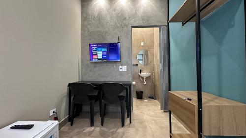 a bathroom with a table with chairs and a tv on the wall at Suíte 07 • Praia das Pitangueiras in Guarujá