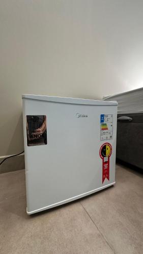 a white refrigerator sitting on the floor in a room at Suíte 08 • Praia das Pitangueiras in Guarujá