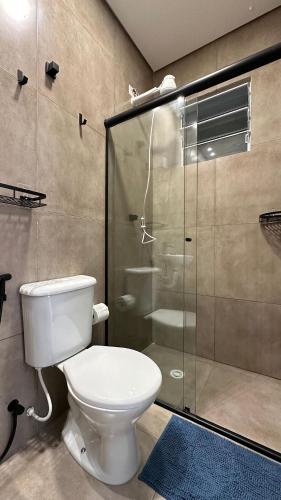 a bathroom with a toilet and a glass shower at Suíte 08 • Praia das Pitangueiras in Guarujá