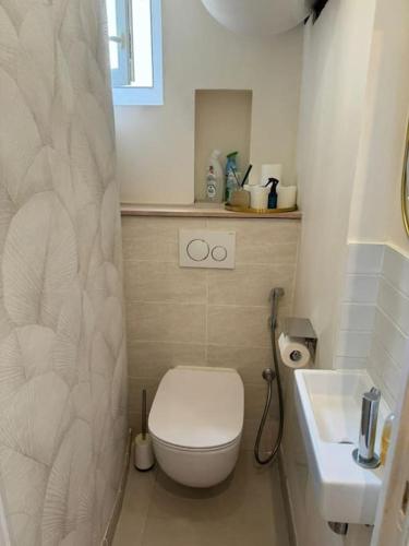 une salle de bain blanche avec des toilettes et un lavabo dans l'établissement Charmant Appartement Alésia, à Paris