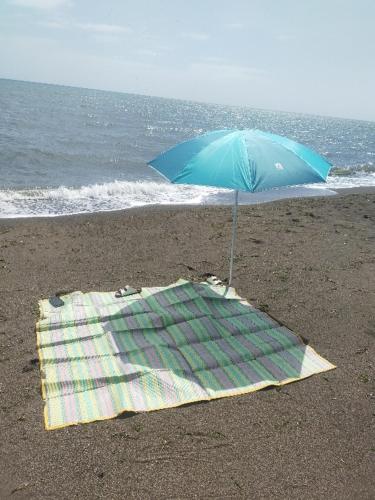 a blue umbrella and a towel on the beach at Beachfront Prime Villa 2 with Private Pool in Calubcub Segundo