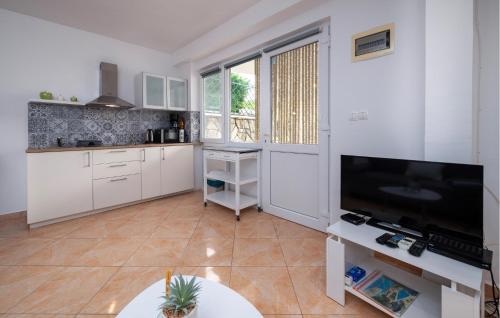 a kitchen with white cabinets and a flat screen tv at Gorgeous Home In Labin in Labin