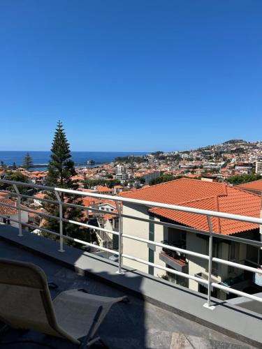 a chair on a balcony with a view of a city at Funchal Casa in Funchal