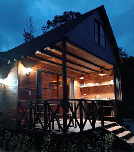a log cabin with a deck at night at Cabaña Momotus II in Concepción