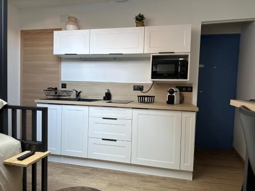 une cuisine avec des armoires blanches et un micro-ondes dans l'établissement Le Studio Bellifontain, à Fontainebleau