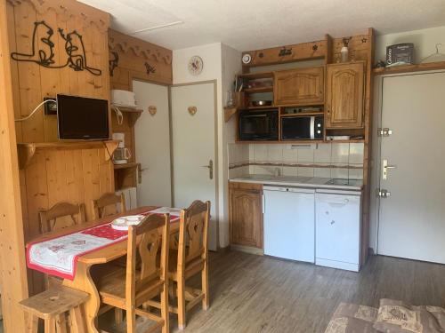 une cuisine avec une table et des chaises et une cuisine avec des placards en bois dans l'établissement Appart cosy avec balcon pour 4 personnes aux Menuires - FR-1-452-137, aux Menuires