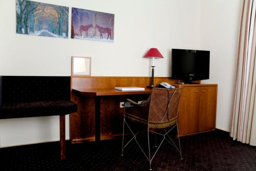 a room with a desk with a television and a chair at Hotel Restaurant Piärdestall Hövelhof in Hövelhof