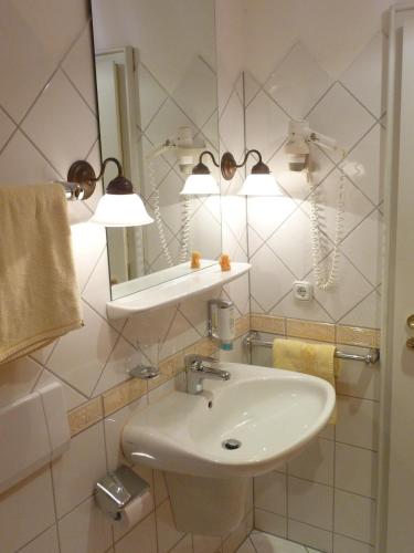 a white bathroom with a sink and a mirror at Hotel Restaurant Piärdestall Hövelhof in Hövelhof