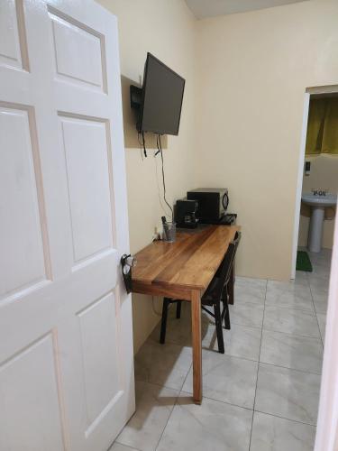 a room with a wooden table with a television on the wall at Viva Violas in Port Antonio