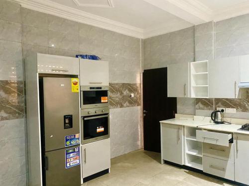 a kitchen with a stainless steel refrigerator and white cabinets at SMK Luxury Apartments Ho in Kodjobi