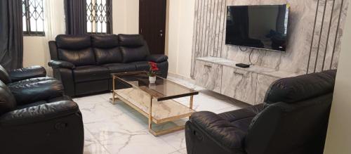 a living room with two leather couches and a television at SMK Luxury Apartments Ho in Kodjobi