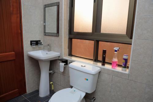 a bathroom with a toilet and a sink at Daisy's Apartments in Bwebajja