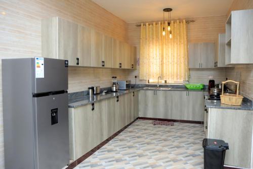 a large kitchen with white cabinets and a refrigerator at Daisy's Apartments in Bwebajja