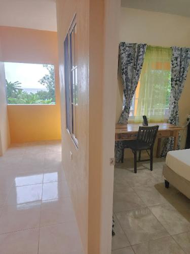 a room with a bed and a desk and a window at Viva Violas in Port Antonio