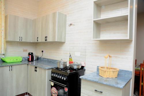 a kitchen with a black stove and white cabinets at Daisy's Apartments in Bwebajja