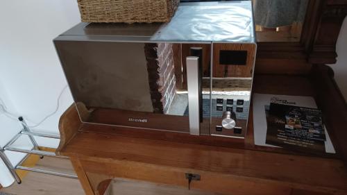 Un four micro-ondes est installé au-dessus d'une table en bois. dans l'établissement La Petite Maison Dans La Prairie, à Écommoy