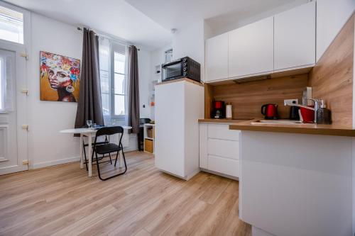 une cuisine avec un réfrigérateur blanc et une table dans l'établissement Charmante Maisonnette à deux pas de la plage, à Châtelaillon-Plage