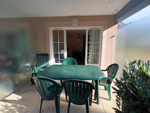 a green table and chairs on a patio at Au pied de la Dordogne in Argentat