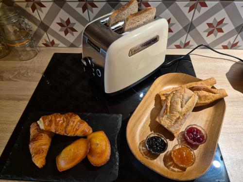 een tafel met brood en croissants en een broodrooster bij Côté Tour in Orcet