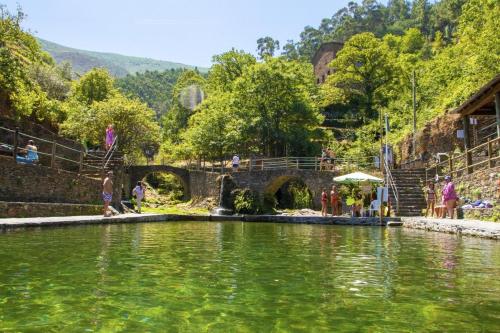 a large body of water with people standing around it at Encanto de Xisto in Piódão